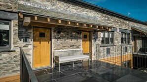 A stone building with a wooden door, a bench, and a balcony with a railing. - 3 Bed in Windermere (oc-lr228) (Windermere)