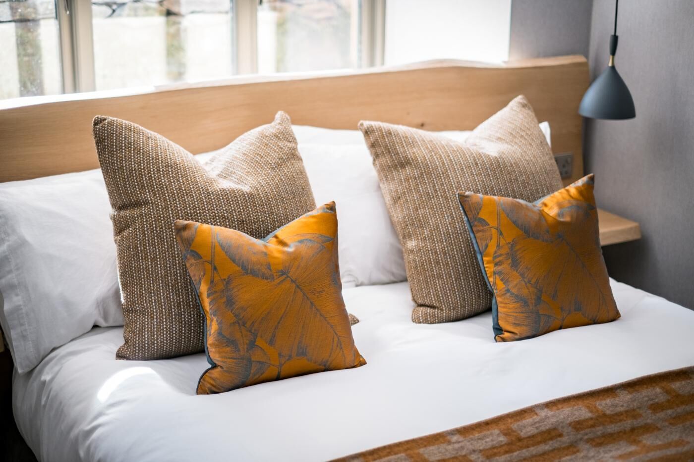 Ein Bett mit weißer Bettwäsche, einem Holzkopfende und mehreren Kissen.