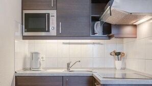 A modern kitchen with a built-in microwave, a coffee maker, and a stainless steel sink. - Ferienwohnung Seepark Sellin mit Ahoi Badewelt & Balkon (Sellin)