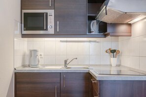A modern kitchen with a built-in microwave, a coffee maker, and a stainless steel sink. - Ferienwohnung Seepark Sellin mit Ahoi Badewelt & Balkon (Sellin)