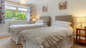 Een hotelkamer met twee bedden, een raam met gordijnen, een radiator en kunst aan de wanden.