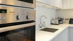 Une cuisine moderne équipée d’appareils électroménagers en acier inoxydable, d’une horloge numérique et d’un évier avec un robinet.