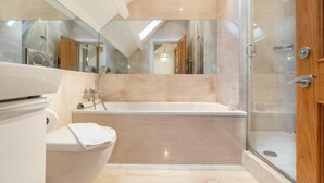 Une salle de bain moderne avec une baignoire sur pieds, une douche à parois de verre et un grand miroir.