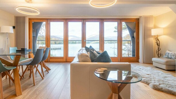 Un salon moderne avec une table en verre, un canapé en cuir et une vue sur un lac.