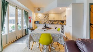 Un ambiente compatto con zona pranzo, angolo cottura e vista tramite una porta scorrevole.