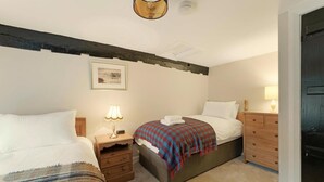 A bedroom with two beds, a nightstand with a lamp, a dresser, and a framed picture on the wall. - 3 Bed in Chapel Stile (oc-lr202) (Chapel Stile)
