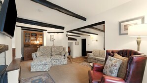 A living room with a sofa, a leather armchair, a patterned rug, and a wooden cabinet. - 3 Bed in Chapel Stile (oc-lr202) (Chapel Stile)