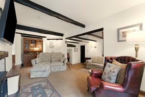 A living room with a sofa, a leather armchair, a patterned rug, and a wooden cabinet. - 3 Bed in Chapel Stile (oc-lr202) (Chapel Stile)