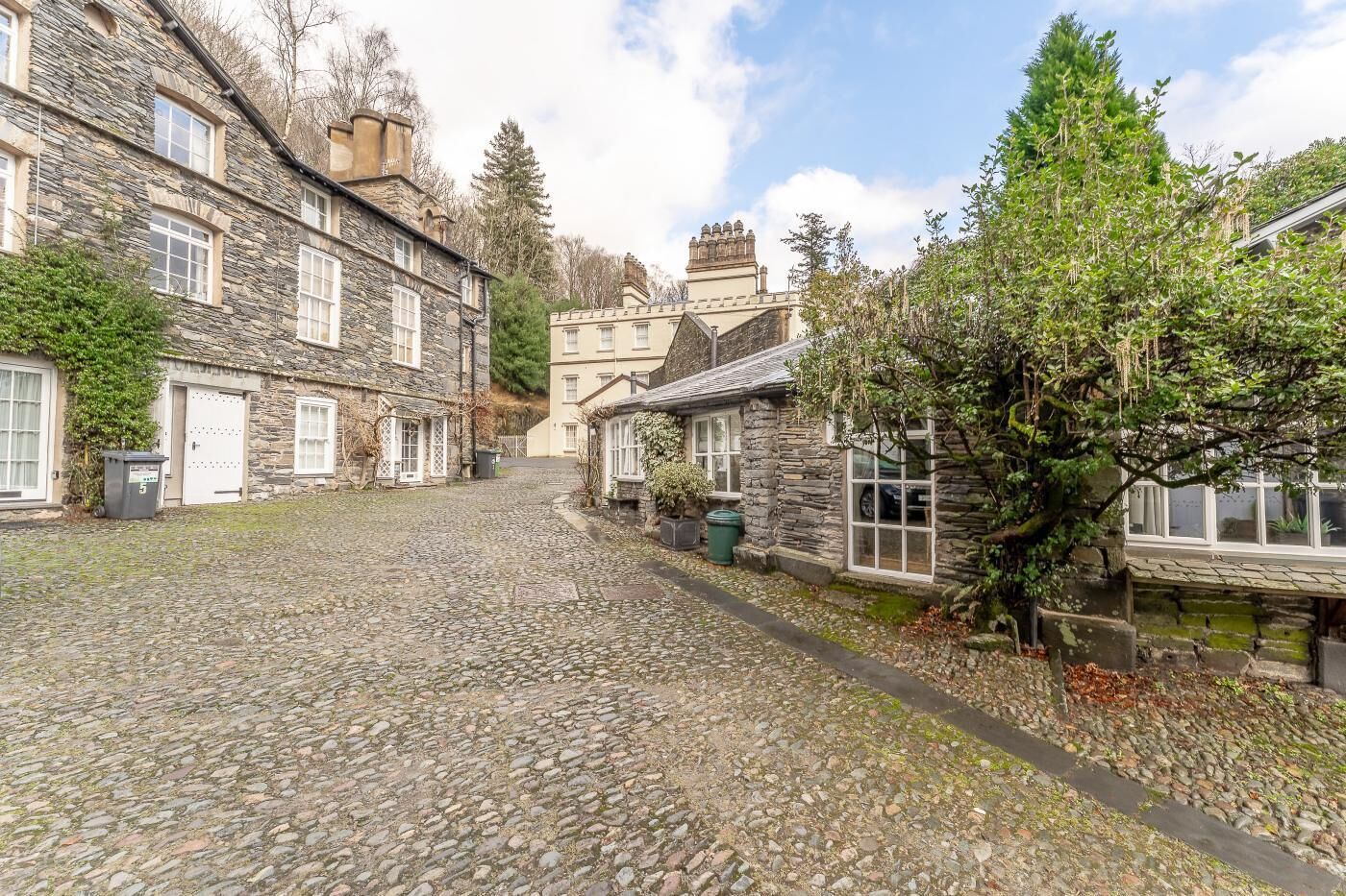 A cobblestone street lined with stone buildings, a narrow path, and a small body of water.