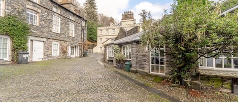 A cobblestone street lined with stone buildings, a narrow path, and a small body of water.