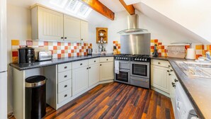 A kitchen with a gas stove, oven, and a tiled backsplash. - 2 Bed in Ambleside (oc-lr041) (Ambleside)