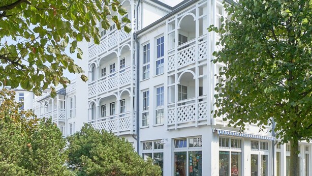 Um edifício branco com várias varandas e grandes janelas.
