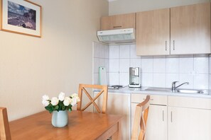 A kitchen with wooden cabinets, a white countertop, a sink, and a coffee maker. - Helle und Gemutliche Ferienwohnung mit Balkon in Sellin (Sellin)