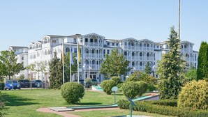 A large, white, multi-story building with a symmetrical facade, surrounded by well-maintained lawns and trees. - Liebevoll Eingerichtete Ferienwohnung fur 4 mit Balkon in Sellin (Sellin)