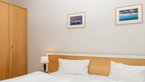 A hotel room with a bed, a wooden wardrobe, a nightstand with a lamp, and two framed pictures on the wall. - Liebevoll Eingerichtete Ferienwohnung fur 4 mit Balkon in Sellin (Sellin)