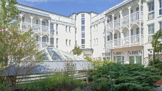 A multi-story building with balconies, a greenhouse, and dense shrubbery. - Liebevoll Eingerichtete Ferienwohnung fur 4 mit Balkon in Sellin (Sellin)