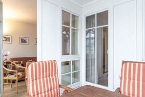 A room with a wooden table, striped chairs, a sofa, and a sliding glass door leading to a balcony. - Liebevoll Eingerichtete Ferienwohnung fur 4 mit Balkon in Sellin (Sellin)