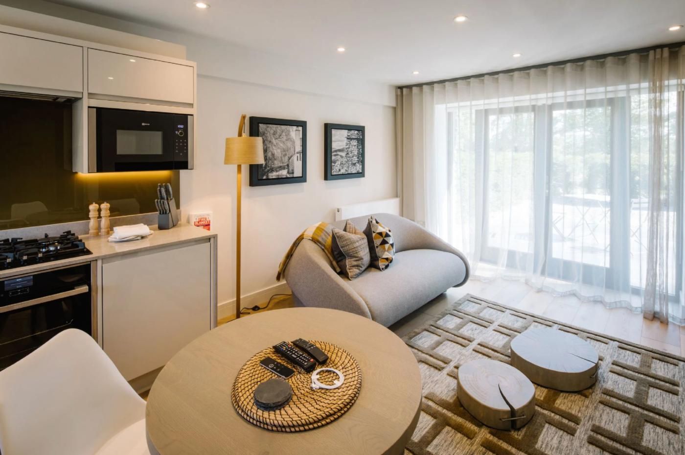 A modern living room with a sofa, a dining table, and a kitchen area with a microwave.