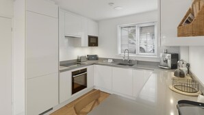 Een moderne keuken met witte kasten, een inbouwoven, een spoelbak en een koffieapparaat.