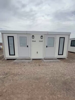 Une structure mobile dotée de deux portes portant les numéros 104A et 104B, d’une petite fenêtre et d’une poignée en métal.