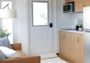 Une cuisine moderne avec des meubles en bois, un four à micro-ondes et un plan de travail blanc.