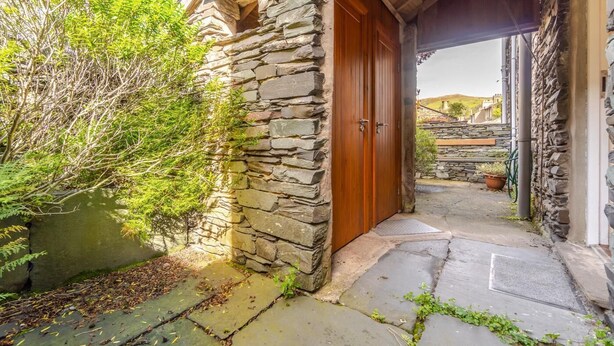 Ein Steinhaus mit einer Holztür, einem Steinweg und einem kleinen Garten.