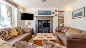 Ein gemütliches Wohnzimmer mit zwei Sofas, einem Kamin, einem Flachbildfernseher und einem Bücherregal.