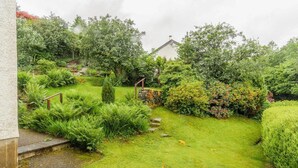 Un jardin luxuriant, avec une grande variété de plantes, et un escalier en pierre menant à un bâtiment.