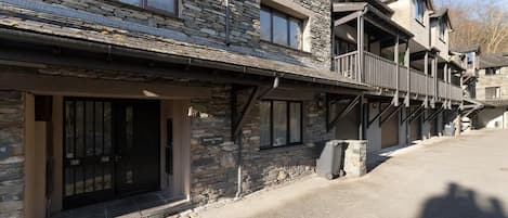 A stone building with multiple balconies, a covered entrance, and a clear sky.