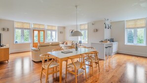 A spacious living area with a wooden dining table, a sofa set, and a kitchen area with a bar. - 3 Bed in Ambleside (oc-lr223) (Claife)