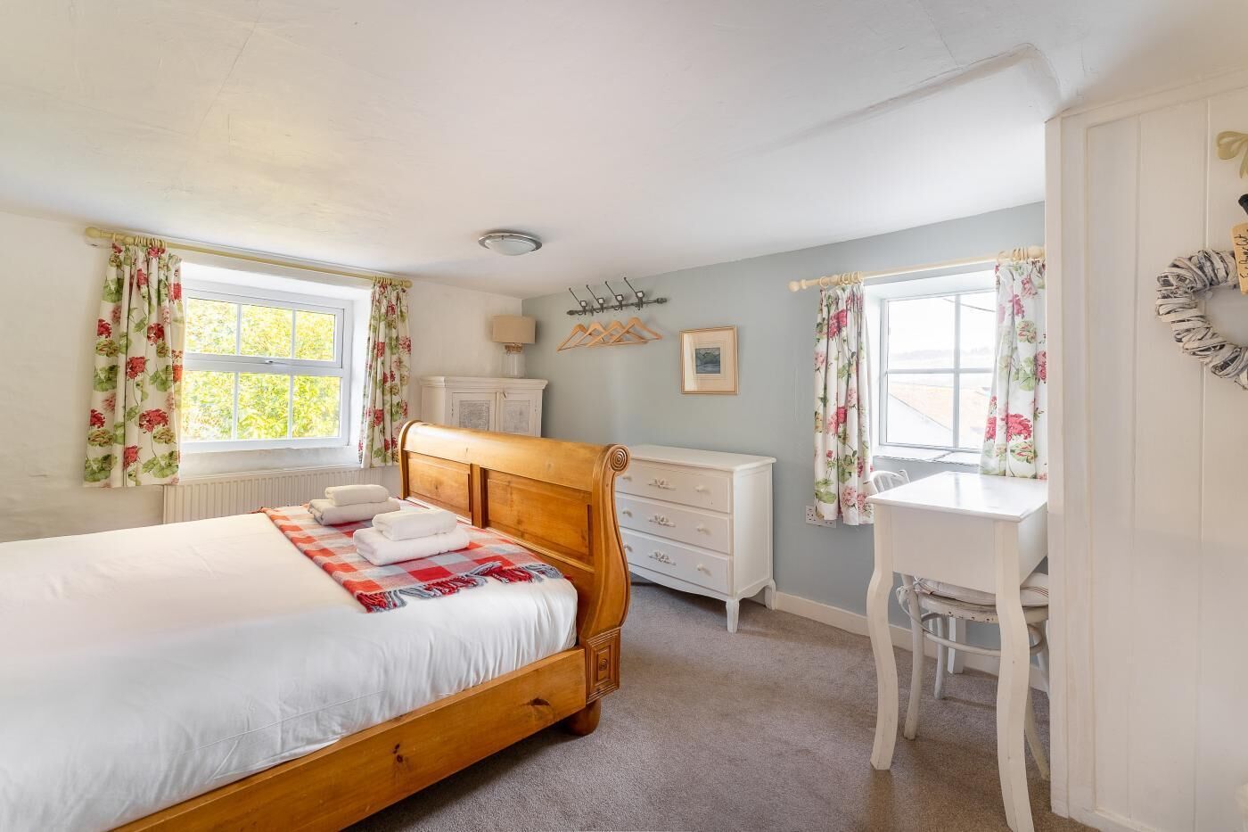 A bedroom with a wooden bed, a white dresser, a desk, and a chair.