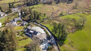 Vue aérienne d’une propriété rurale comprenant une grande maison, une allée et des champs environnants.