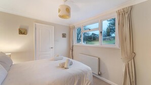 Une chambre à coucher avec un lit, une fenêtre avec des rideaux, un radiateur et une porte.