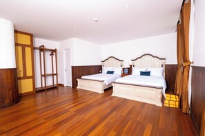 Habitación de hotel con dos camas, suelo de madera y un armario con espejo.