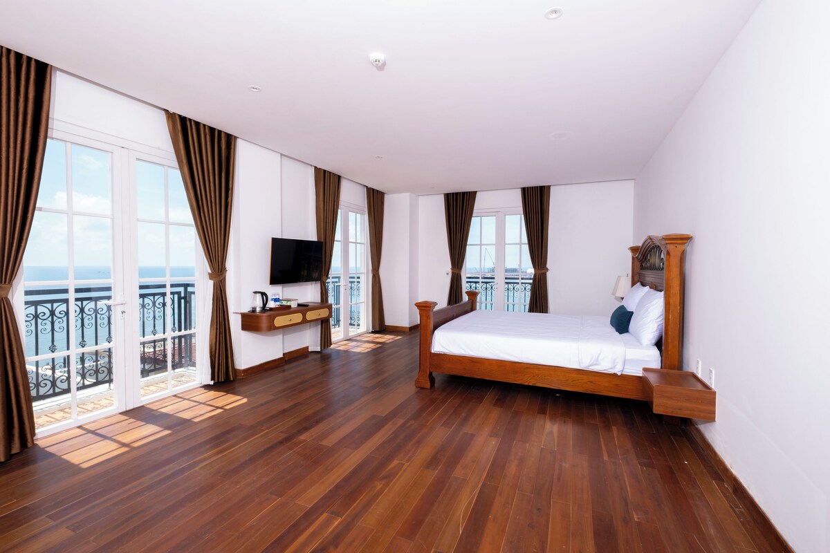 Un dormitorio amplio con una cama grande, televisión y balcón con vistas.