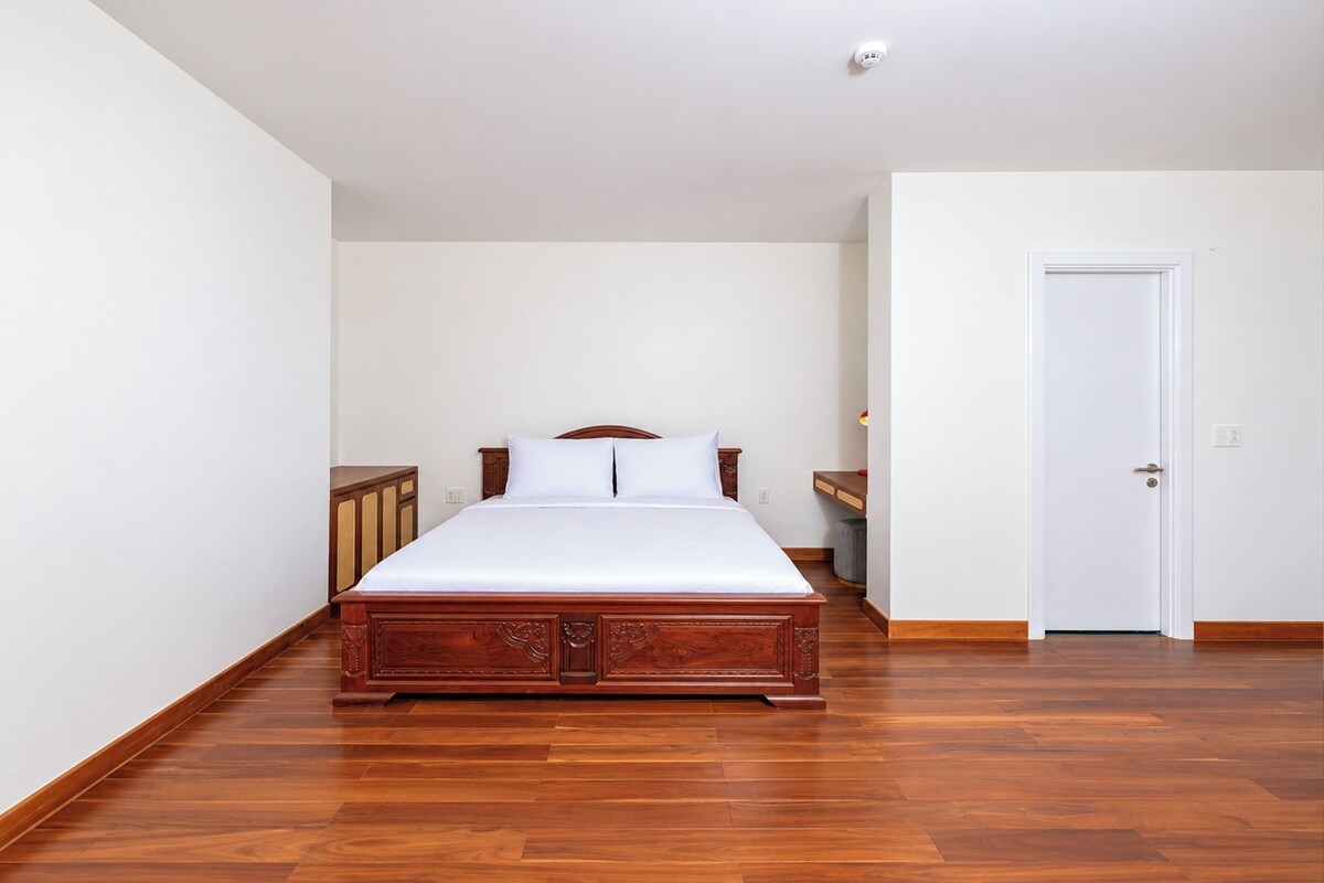 Un dormitorio con cama de madera, paredes blancas y una puerta.