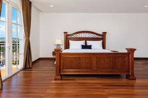 Um quarto espaçoso com uma cama grande, uma mesinha de cabeceira e vista para o exterior.