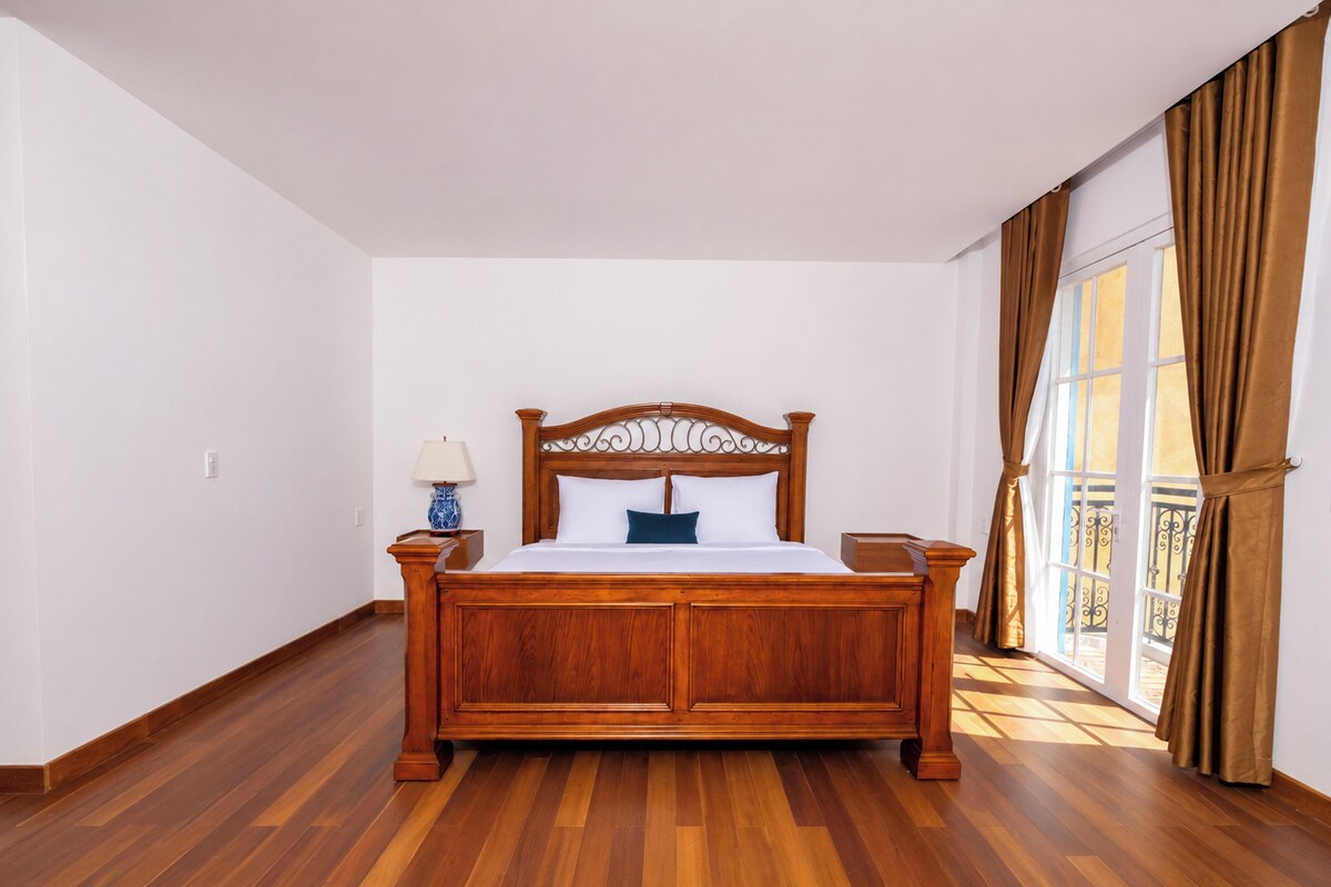 Un dormitorio con una cama de madera, una mesita de noche, una lámpara y una ventana con cortinas.