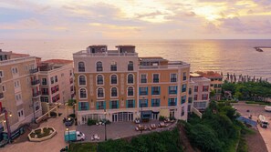 Un hotel de varios pisos con un patio, piscina y vistas al mar.