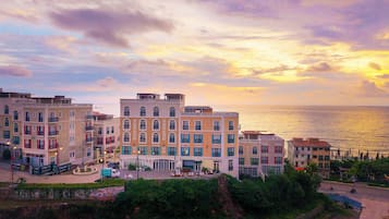 A coastal building with multiple floors, balconies, and a view of the sea.