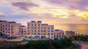 Um edifício à beira-mar com vários andares, varandas e vista para o mar.