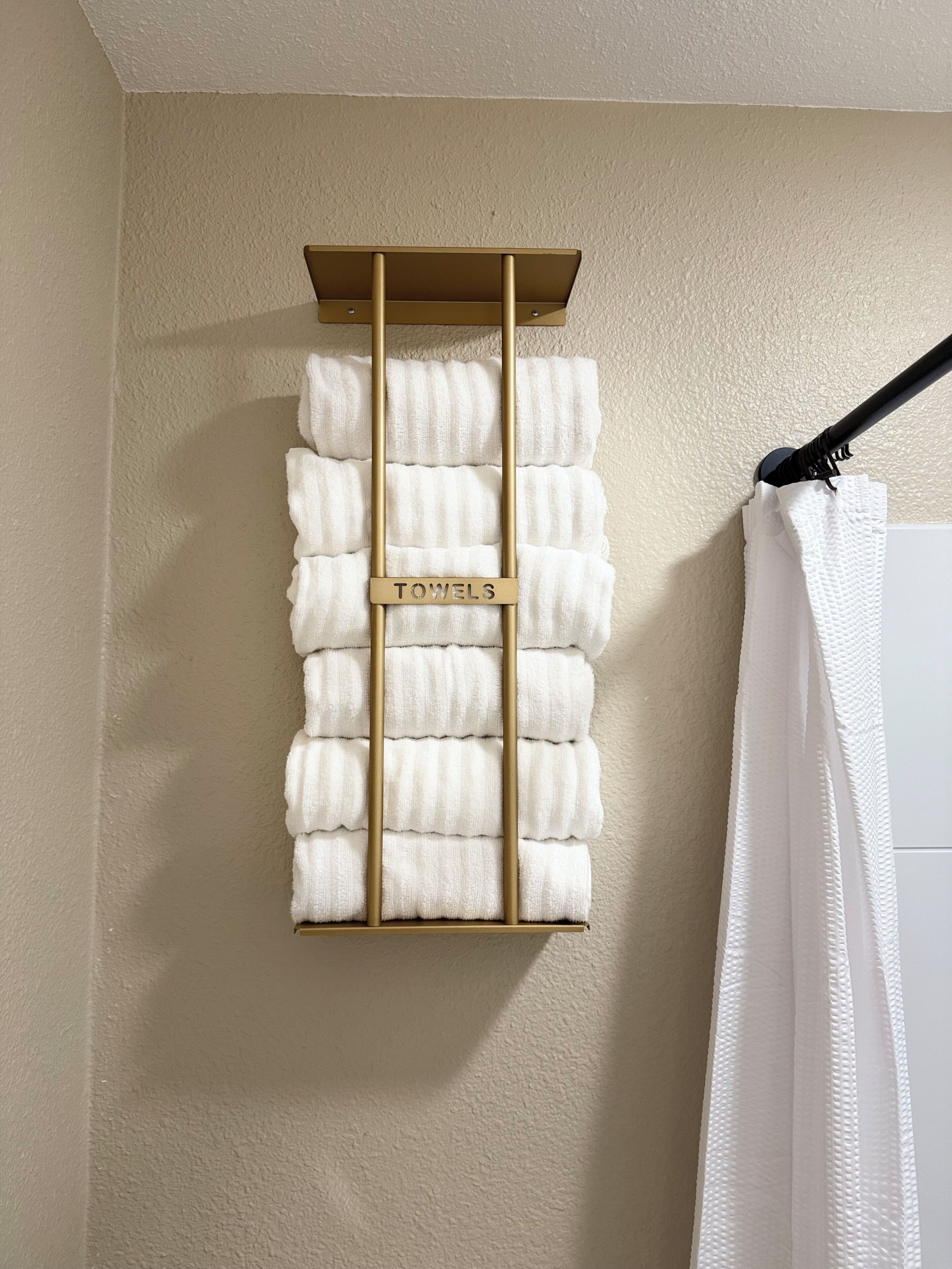 A wall-mounted towel rack with multiple white towels.