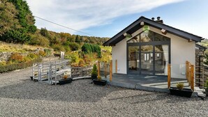 Ein modernes Haus mit einer großen Glasfront, umgeben von Kies und Pflanzen.