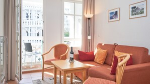 A living room with a sofa, a table, a chair, a bottle of wine, and a lamp. - Charmante Ferienwohnung fur 3 mit Balkon im Seepark Sellin (Sellin)