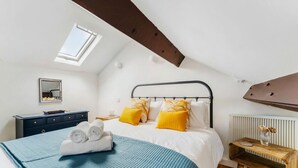 Una camera da letto con un letto, una cassettiera, un comodino, una finestra e un termosifone.