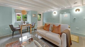A modern living room with a sofa, dining table, chairs, and a coffee table. - 1 Bed in Bowness On Windermere (oc-lr171) (Bowness on Windermere)