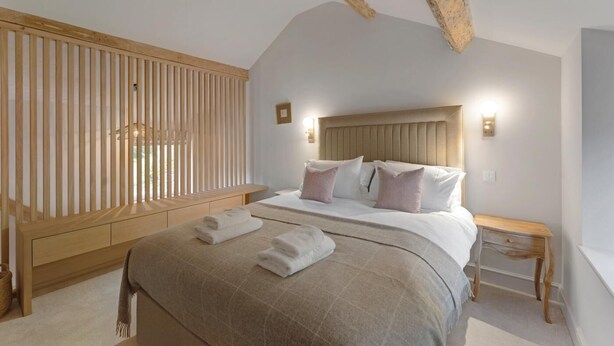 A bedroom with a bed, bedside tables, a wooden headboard, and a slatted wall. - 1 Bed in Bowness On Windermere (oc-lr171) (Bowness on Windermere)