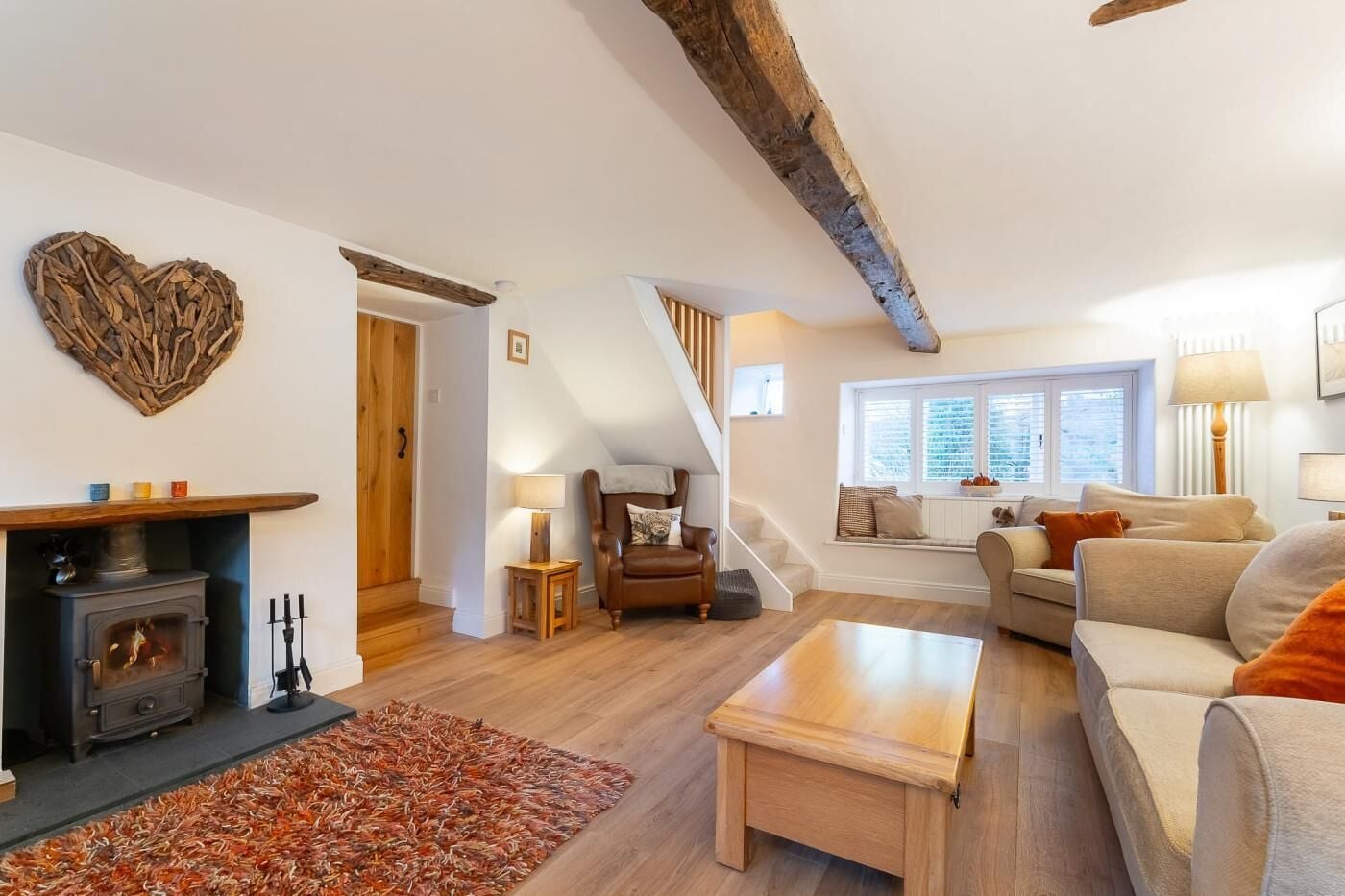 A cozy living room with a fireplace, a sofa, a coffee table, and a staircase leading to an upper level.