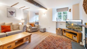 Ein Wohnzimmer mit einer Couch, Sesseln, einem Couchtisch, einem Fernseher, einem Kamin und einem Fenster mit Blick.