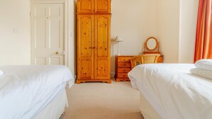 Ein Schlafzimmer mit zwei Betten, einem Holzschrank, einem Schminktisch und einem Spiegel.